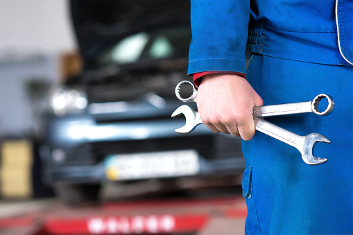 auto repair santa rosa - mechanic holding wrenches and car in background