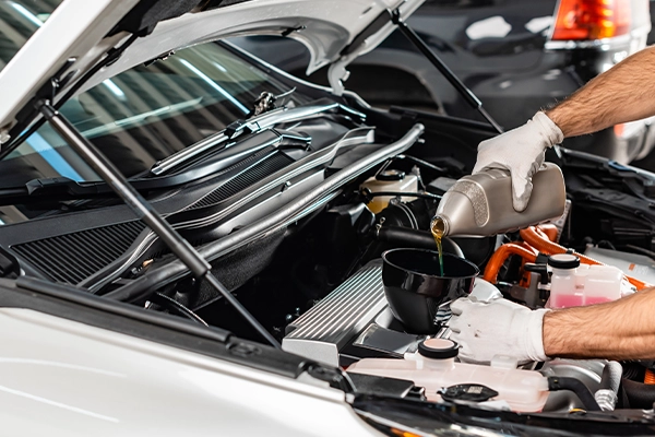 Technician adding motor oil to engine through funnel