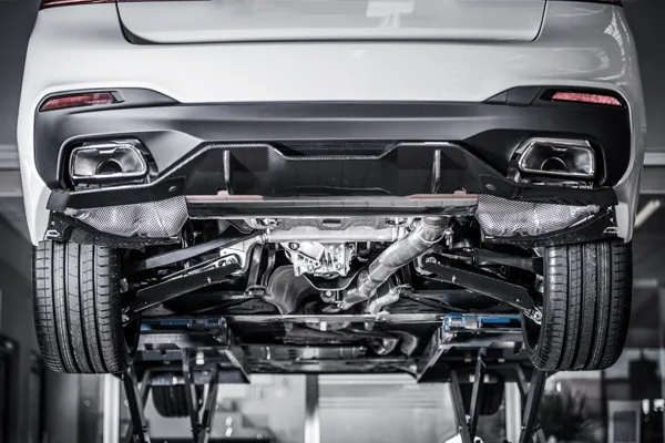 white car on a lift with its suspension system and exhaust system exposed.